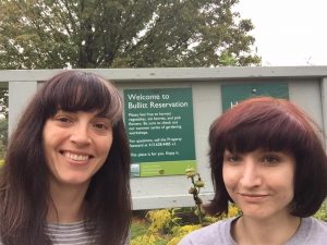 Two smiling women in front of a sign reading "Welcome to the Bullitt Reservation"