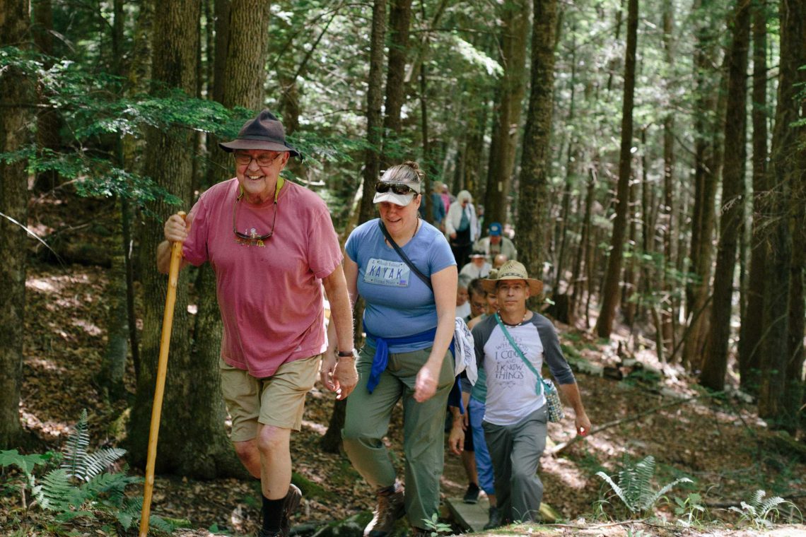 A line of hikers single file on a wooded trail